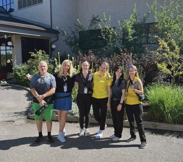 Six people part of a golf team standing together.