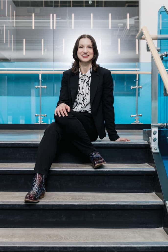 Dr. Ana Nikolic sits in a stairwell, her cowboy boots on display.