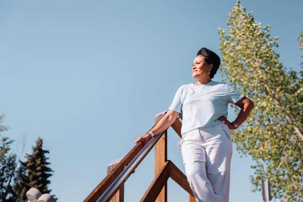 Arbaiza standing with her hand on her hip, looking off to the side with a blue sky behind her.
