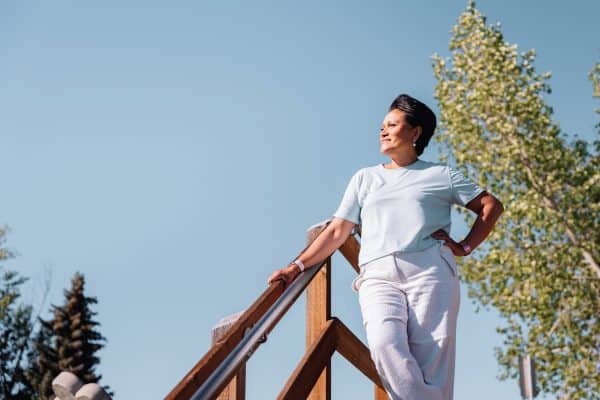 Arbaiza standing with her hand on her hip, looking off to the side with a blue sky behind her.