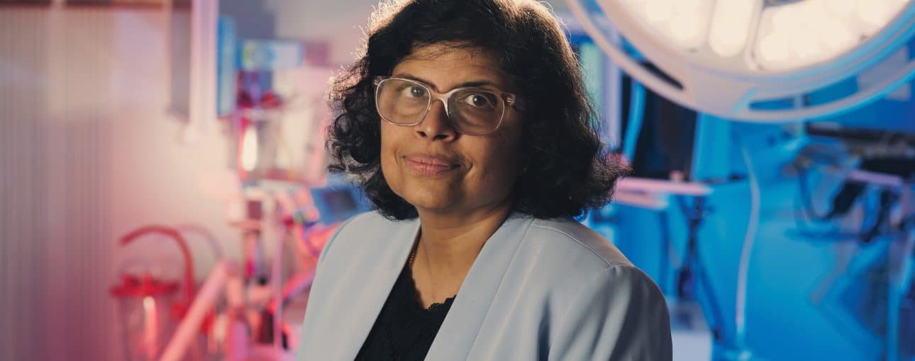 Dr. Geetha Menon in a blue blazer standing an a brachytherapy suite.