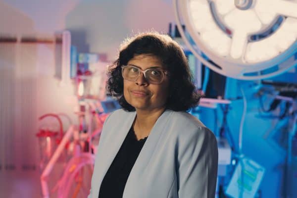 Dr. Geetha Menon in a blue blazer standing an a brachytherapy suite.