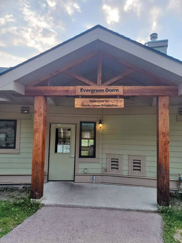 The entrance to a camp cabin with the name Evergreen Dorm.
