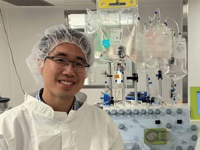 Dr. Michael Chu in a hair net standing in front of medical equipment.