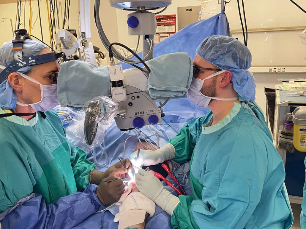 A doctor and resident operating on a patient in the operating room.