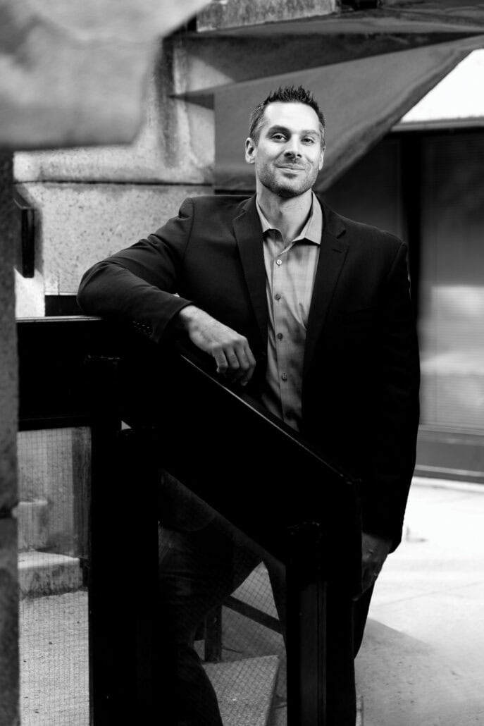 Black and white photograph of a man leaning against the wall.
