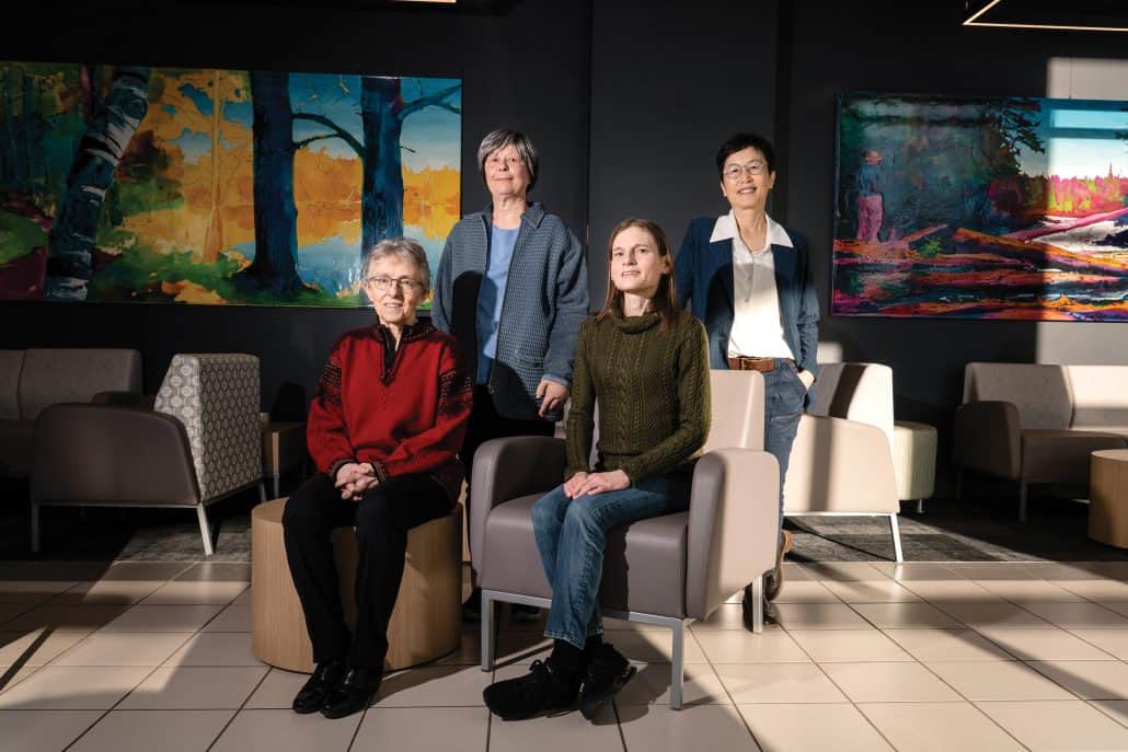 Dr. Ing Swie Goping, Dr. Kristi Baker, Dr. Vickie Baracos and Dr. Roseline Godbout smile at the camera in front of colourful paintings.