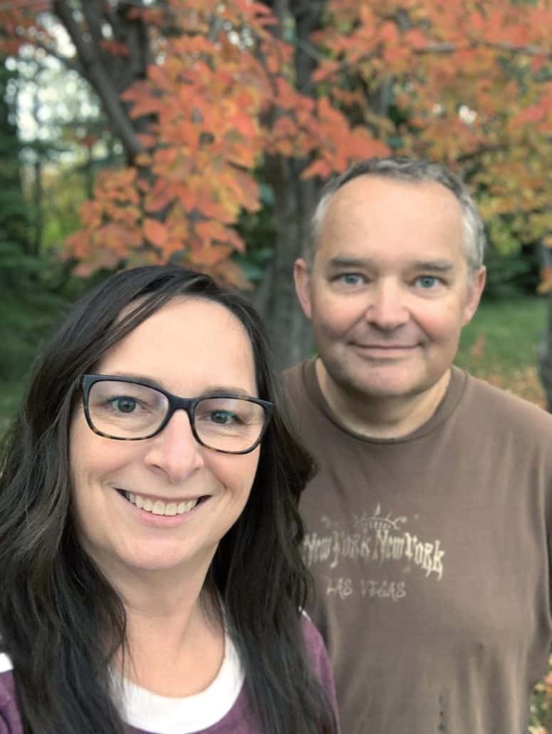 Man and woman smiling with fall leaves behind them.