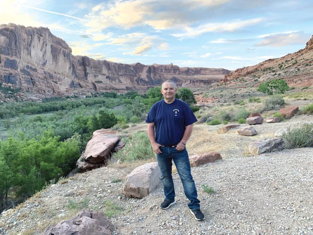 Man stands outside in a canyon surrounded by rocks.