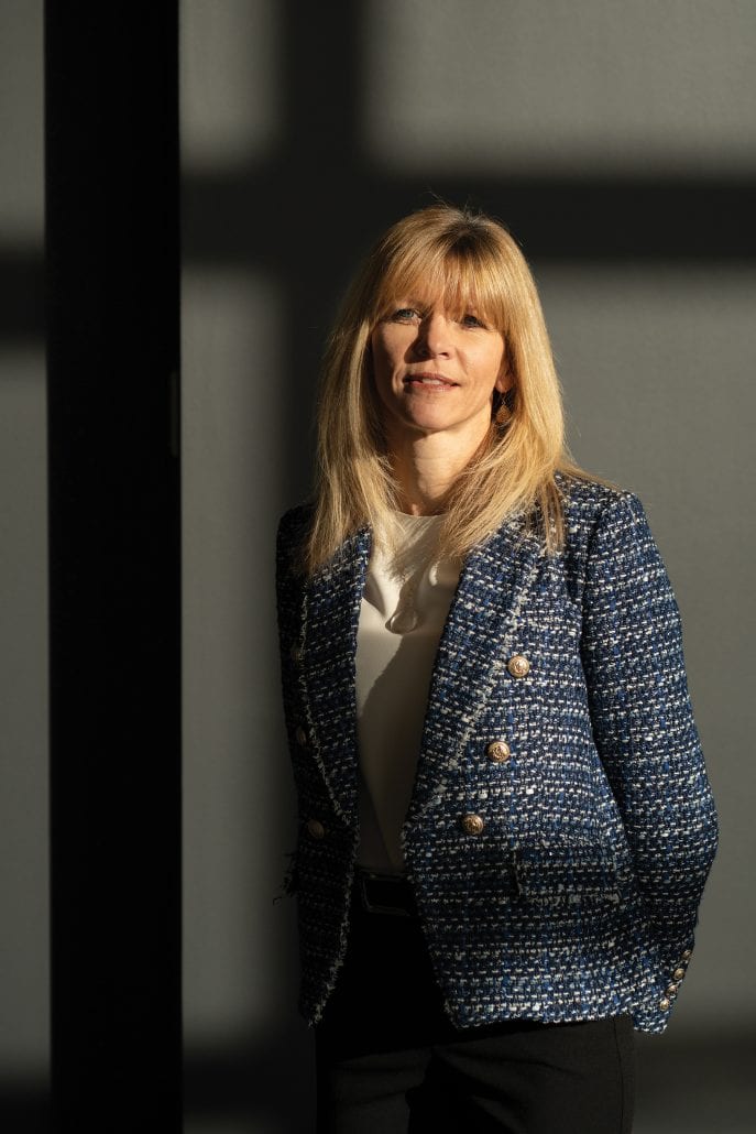 Dr. Helen Steed in a blazer looking into the camera surrounded by shadows from the window.