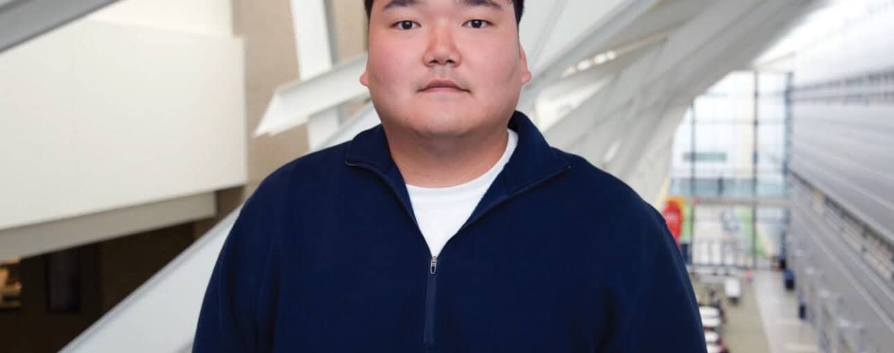 Man in a dark blue sweater looks at the camera.