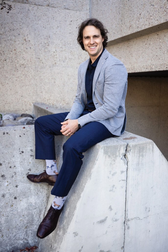 Man sits on a concrete block, smiling at the camera.