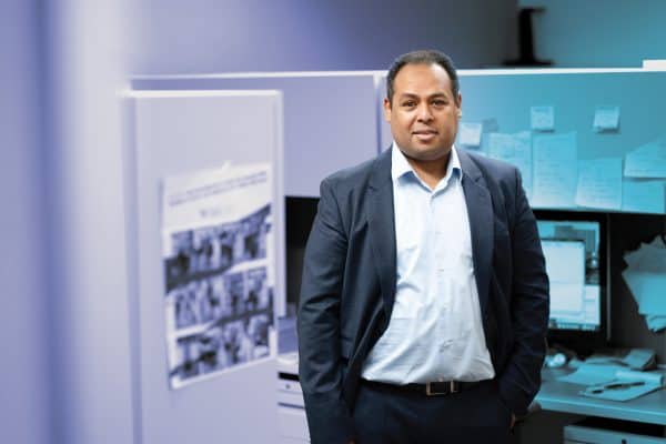 Man in an office standing with his hands in his pockets.