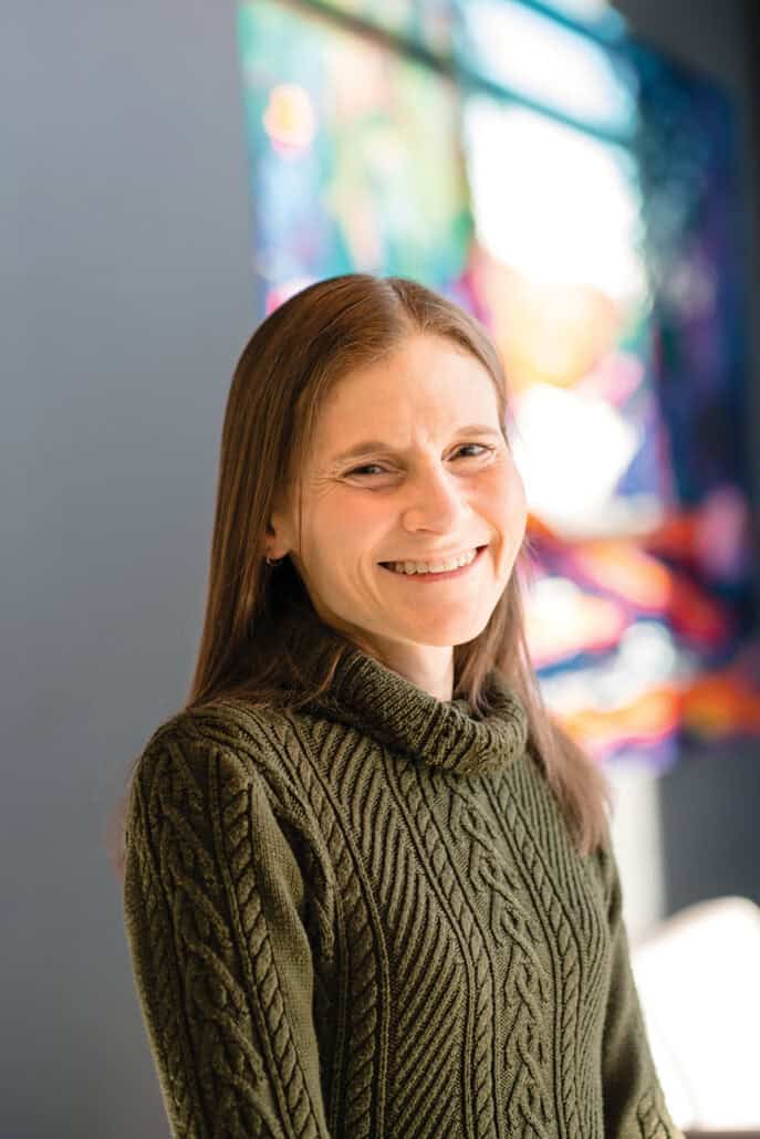 Woman in a green turtle neck smiles at the camera.