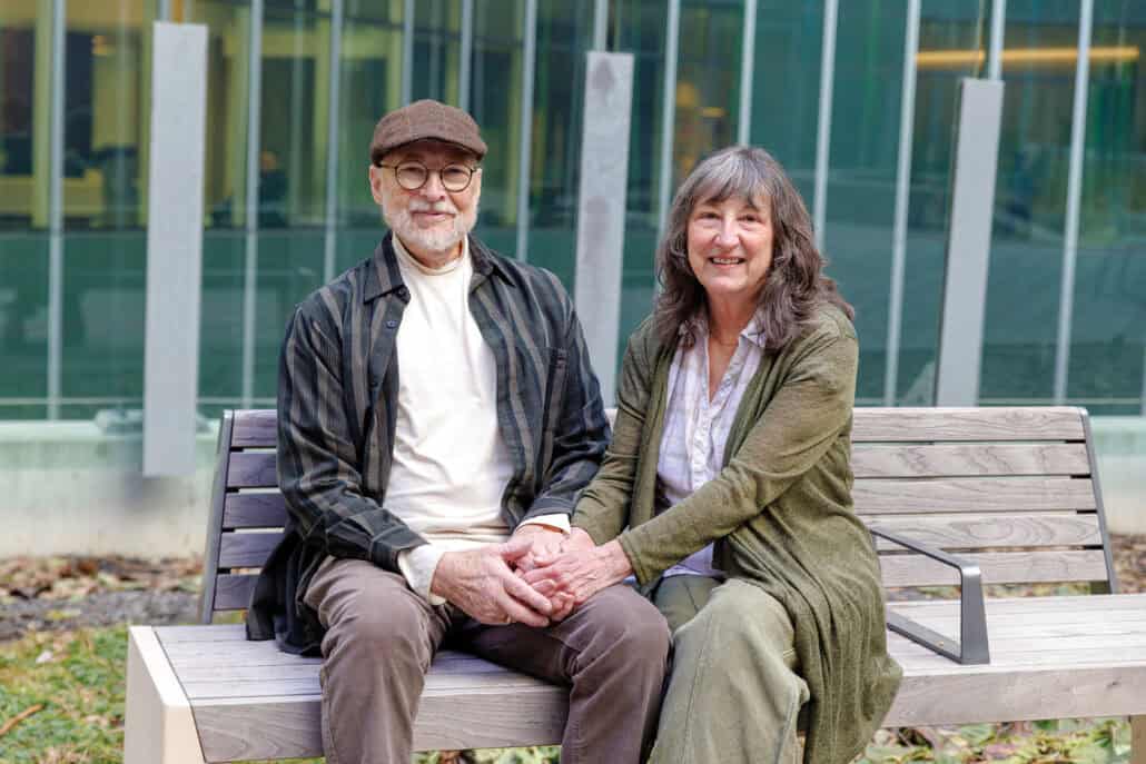 Terry Grant and his wife, Laureen, sit on a bench while holding hands. 