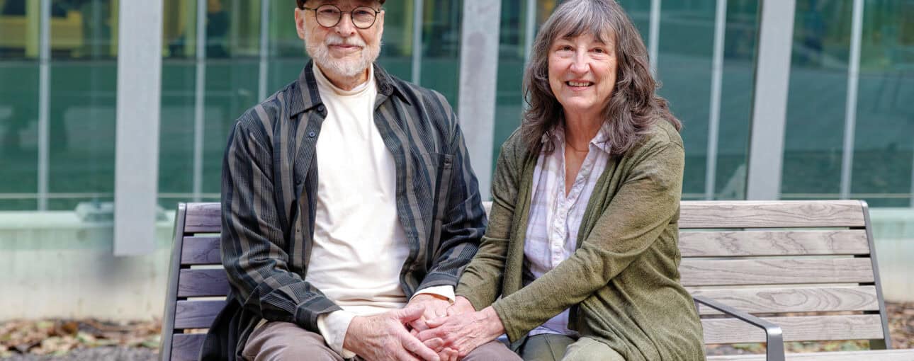 Terry Grant and his wife, Laureen, sit on a bench while holding hands.