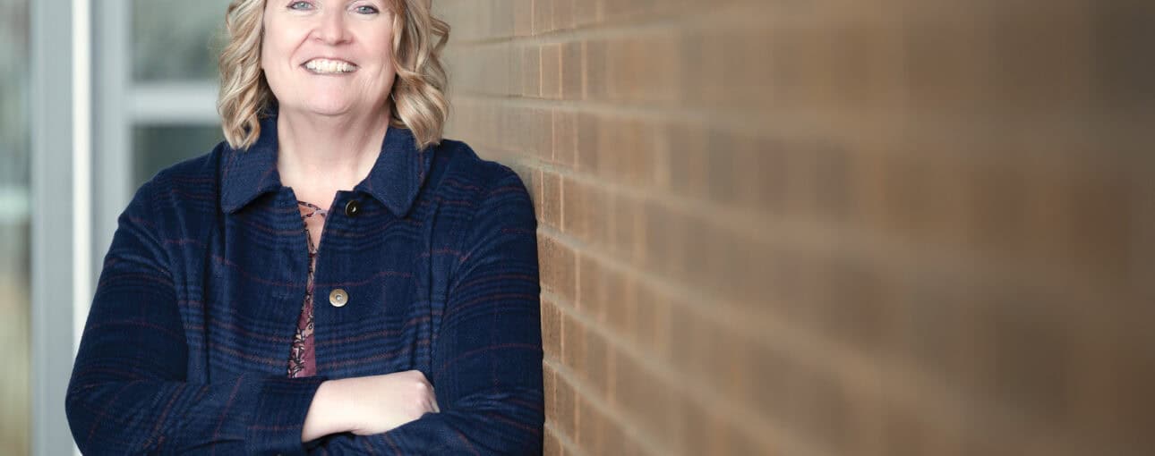Laurie Laughren stands against a brick wall with her arms crossed.