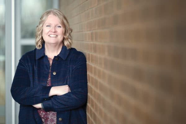 Laurie Laughren stands against a brick wall with her arms crossed.