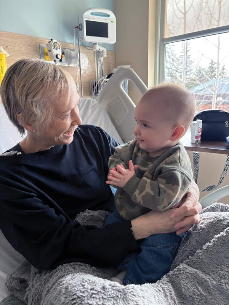 A woman in a hospital bed holds her grandson.