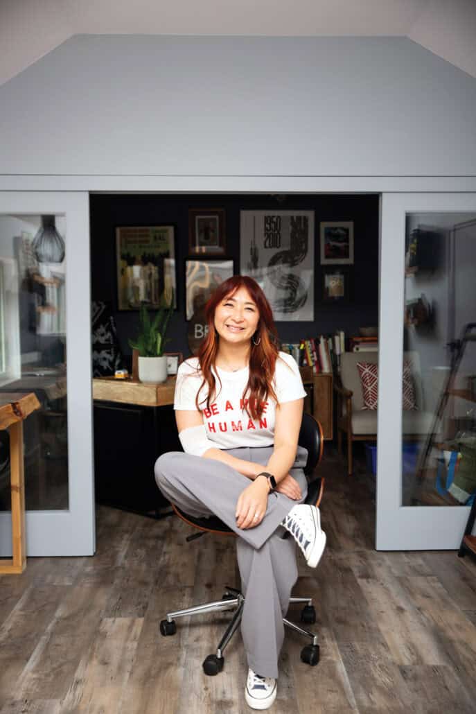 A woman sits in a chair smiling at the camera.