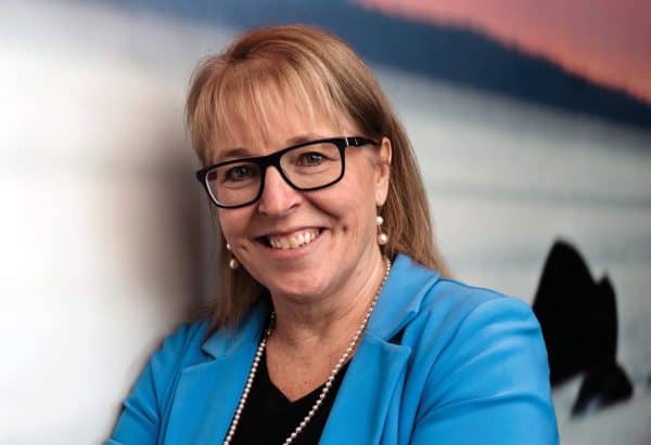 Dr. Linda Watson in a blue blazer crossing her arms and smiling at the camera.