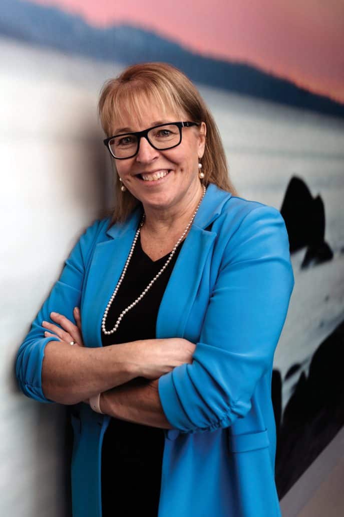 Dr. Linda Watson in a blue blazer crossing her arms and smiling at the camera.