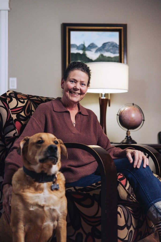 Clinical trials offer hope. 1 Woman sitting in a chair in her home with her dog.