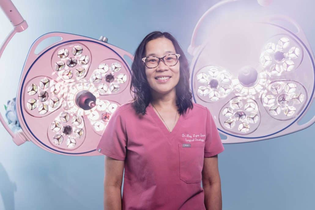 An innovative approach to breast cancer surgery. 1 Doctor in pink scrubs standing in front of operating lights.