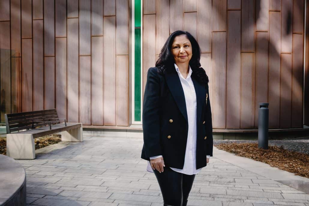 Woman stands outside smiling lightly at the camera.