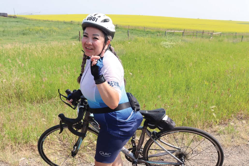 Nhi Ha on her bike with a canola field in the background.