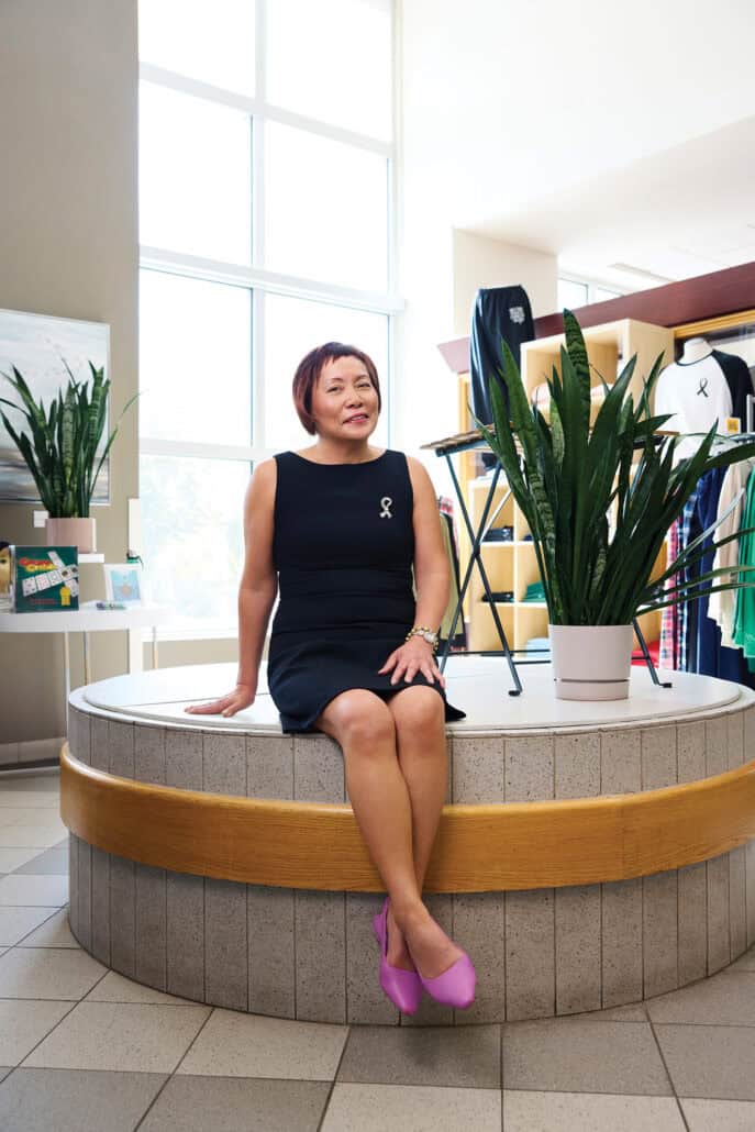 Woman in a black dress sits on a cement pillar in a gift shop.