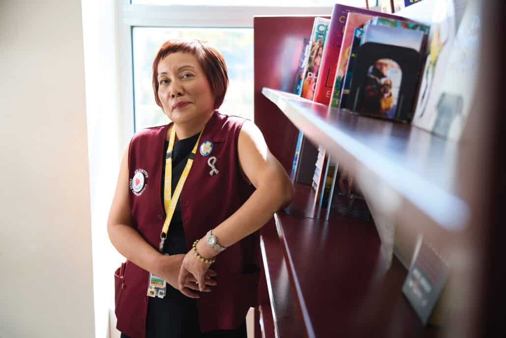 Woman leans up against a burgundy book shelf.