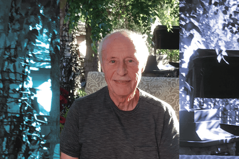 Elderly man smiling at the camera while sitting outside.