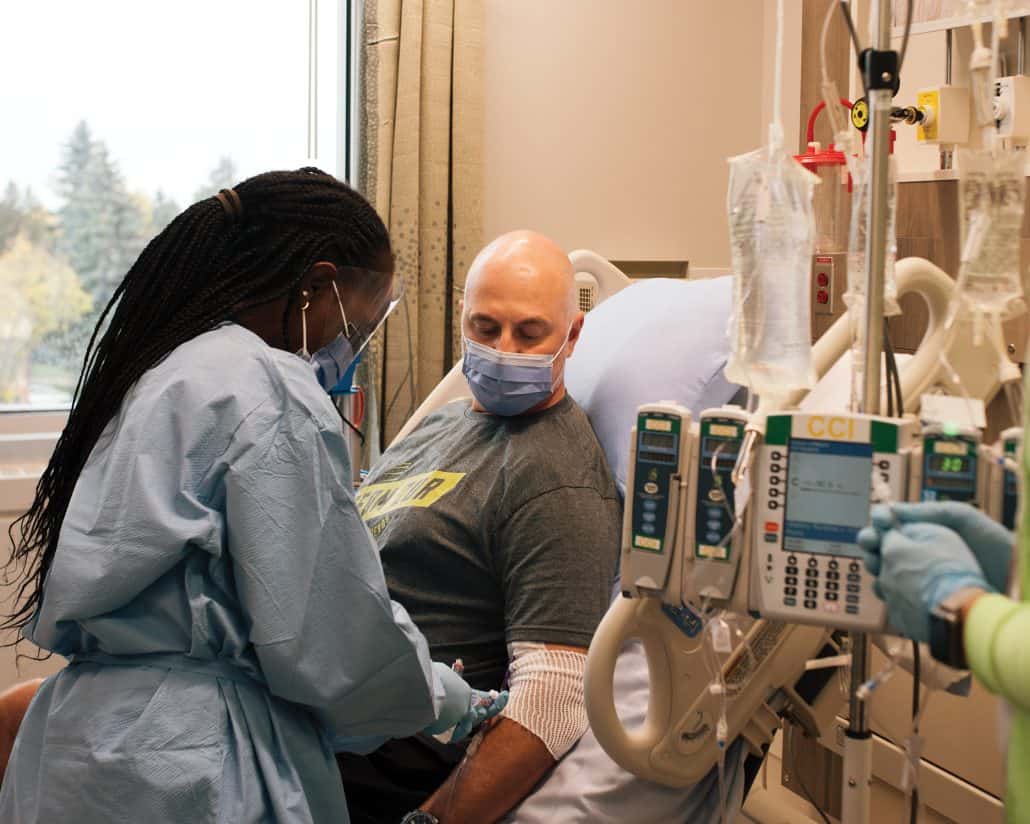 Medical professional draws blood from a patient in a hospital bed.
