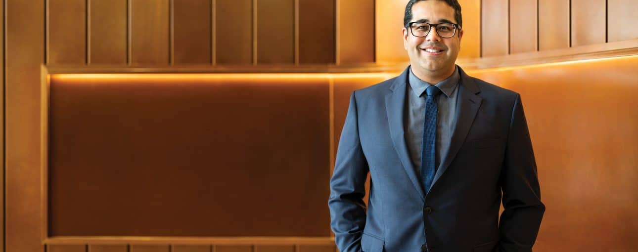 Bright mind. 1 Man in a blue suit against a brown wall.