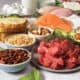 A medley of healthy foods, including raw beef, salmon, avocado, multigrain bread, nuts, eggs, oats and tofu.
