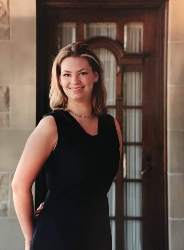 Dr. Rachel Mandel in a black dress with her hands behind her back, smiling at the camera.