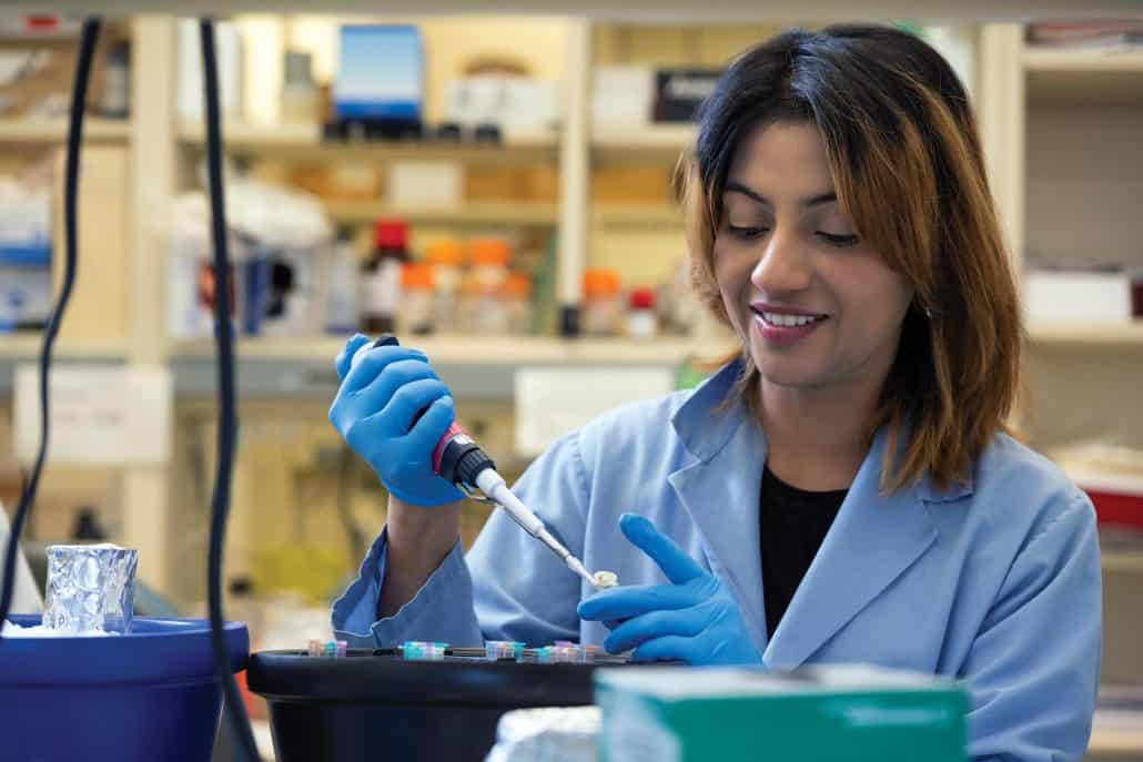 Medical profession in a blue lab coat works on research project.