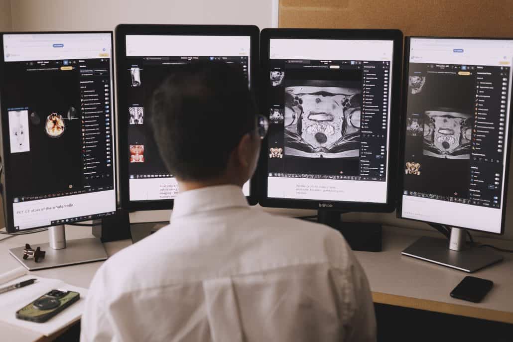 Leading the way. 2 A doctor looking at four screens showing medical results.