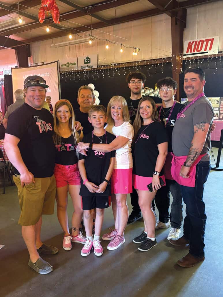 A survivor's purpose 1 A family in matching black t-shirts and some wearing pink shorts pose together during a fundraiser.