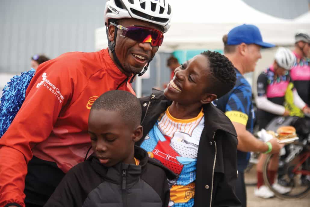 Tendai Mashonganyika in a helmet and riding sunglasses alongside his family looking at him lovingly while celebrating.