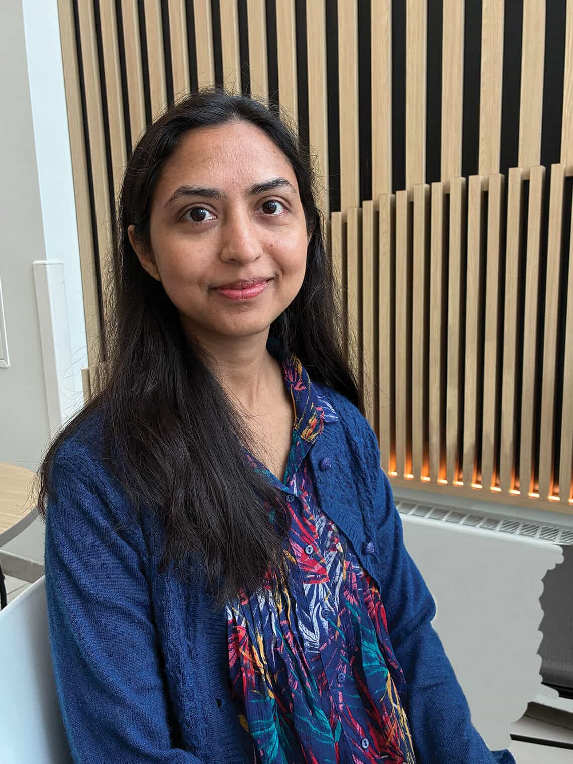 Dr. Zarmina Alam smiles at the camera. Behind her there is a wood-paneled wall. 