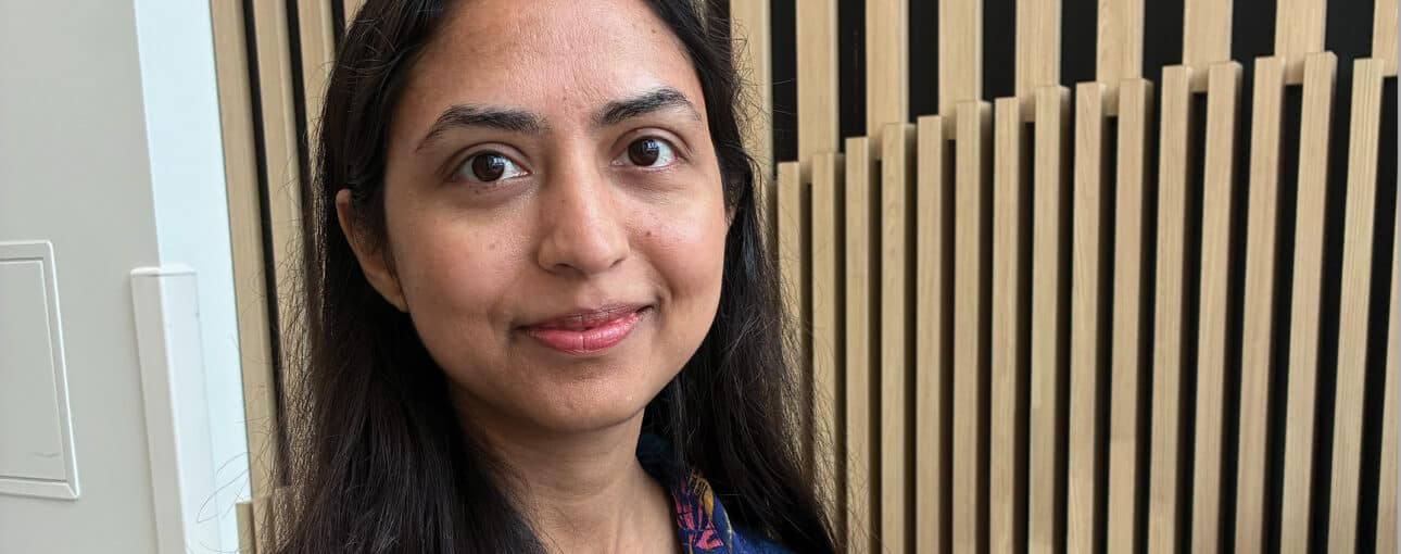 Dr. Zarmina Alam smiles at the camera. Behind her there is a wood-paneled wall.