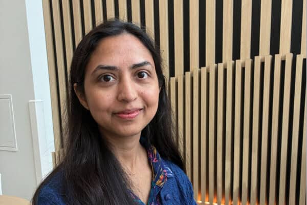 Dr. Zarmina Alam smiles at the camera. Behind her there is a wood-paneled wall.